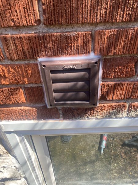 After: Dryer vent hood on brick — flange-to-wall joint cut out and resealed