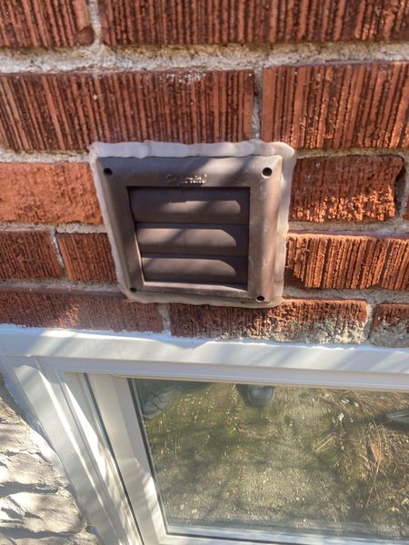 Before: Dryer vent hood on brick — flange-to-wall joint cut out and resealed