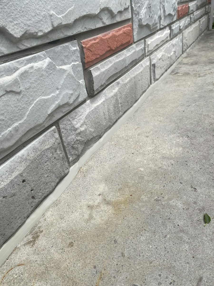 Stone veneer at grade — the base joint sealed in a matching grey