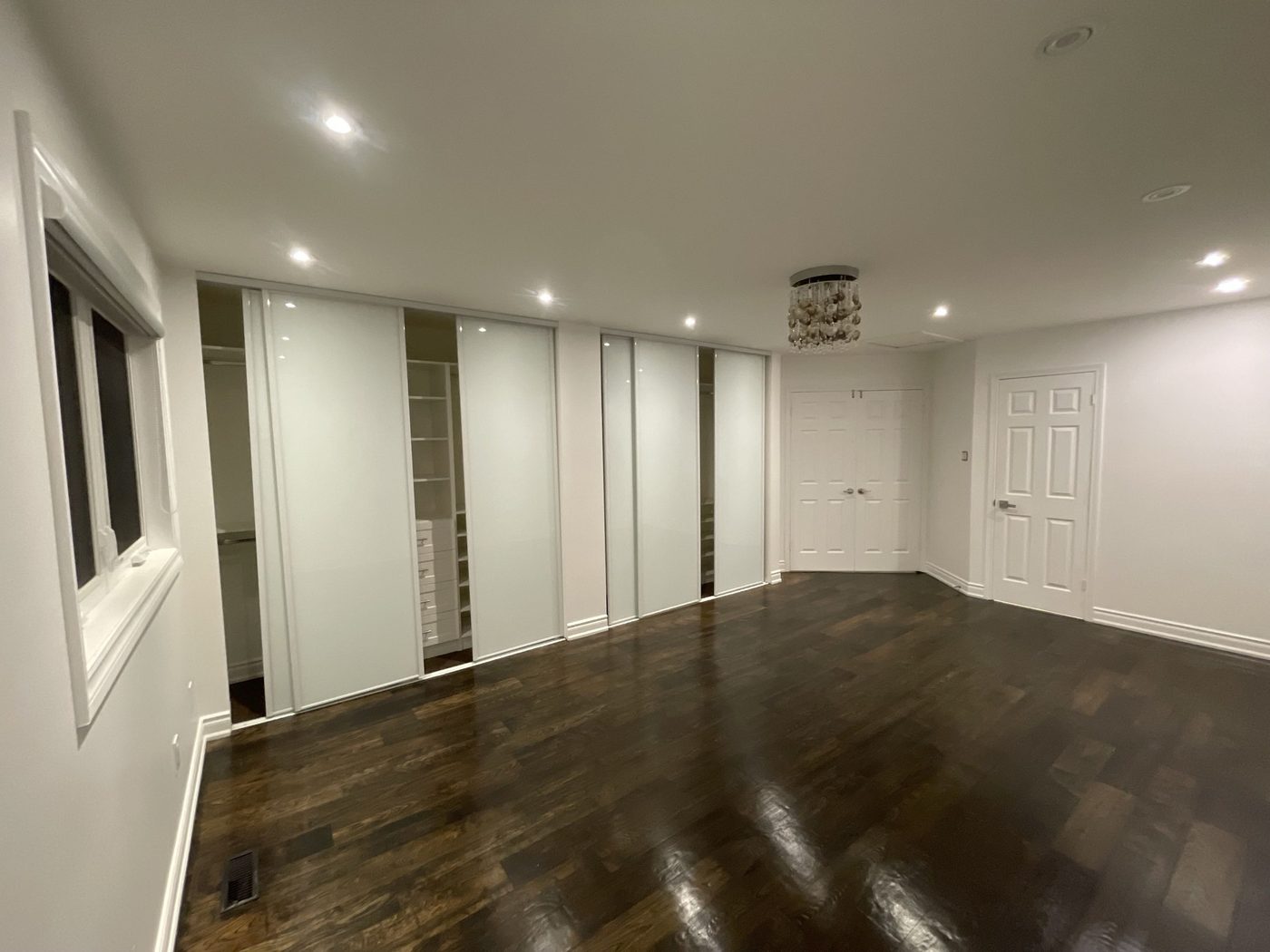 A finished bedroom: white walls and ceiling, trim and doors enamelled, dark hardwood floor — the room handed back clean