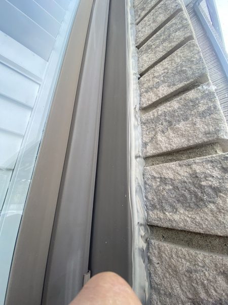 Another contractor's work: a second bead of caulking laid directly on top of the old failed bead at a window frame