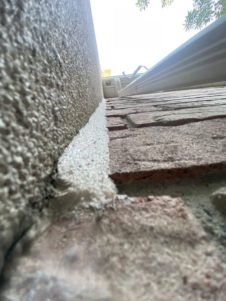 Stucco wall to brick paving: the sealed joint sandblasted so it reads as concrete rather than caulk