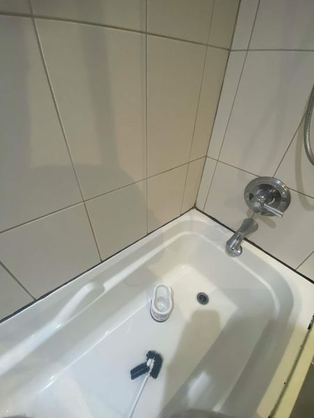 Before: Tub-to-tile joint: the blackened bead stripped out and resealed