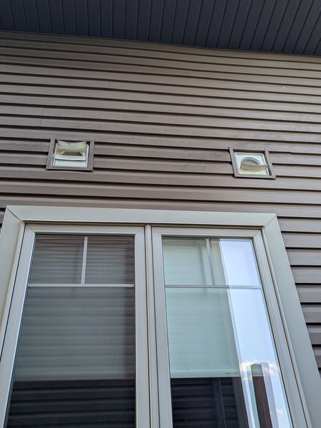 Before: Exhaust vent covers on siding — cracked covers replaced, flanges resealed