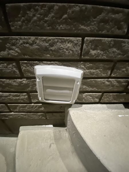 After: Dryer vent on stone — the foam-stuffed hole replaced with a hood, sealed at the flange