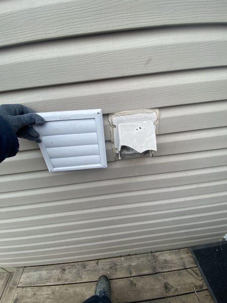 Two exhaust vents on siding — new hood beside the old cover