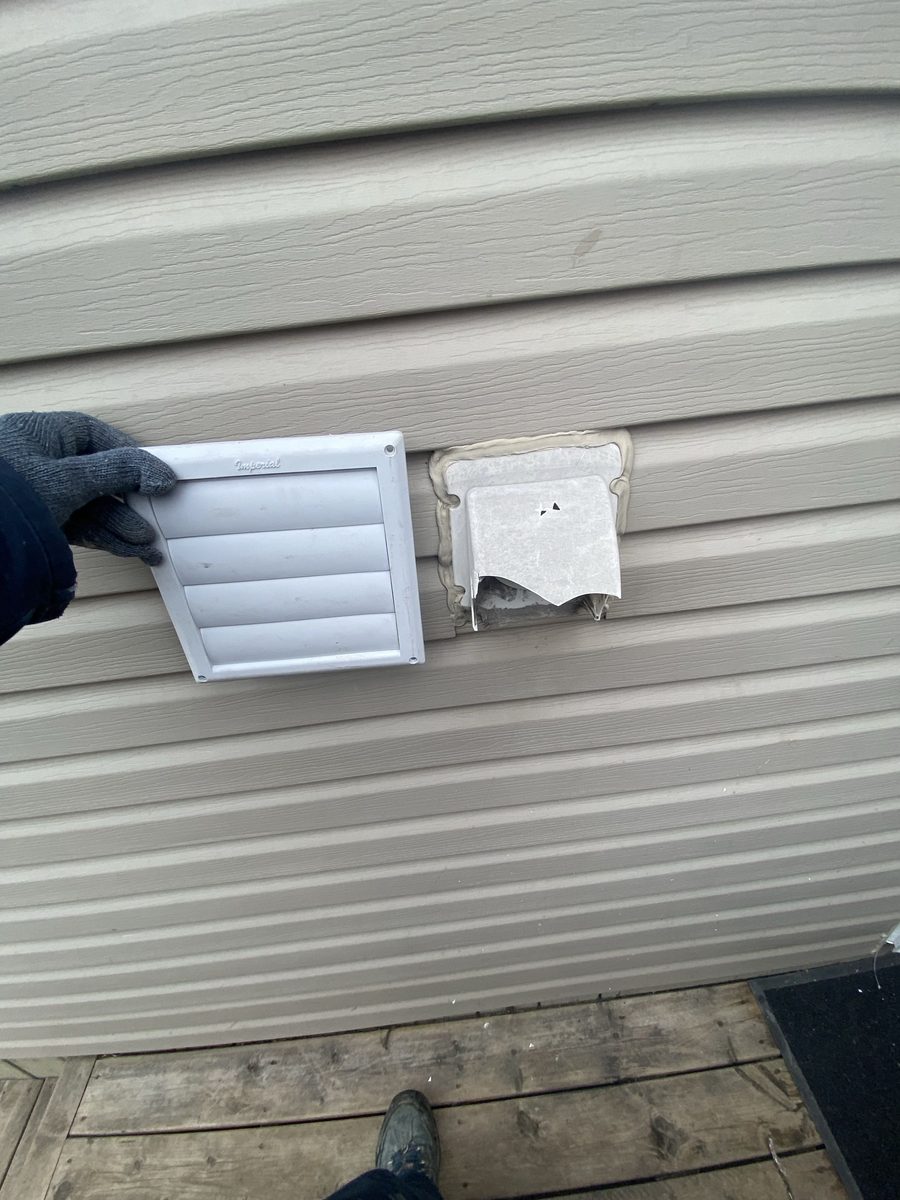 Two exhaust vents on siding — the new hood beside the old cover it replaces